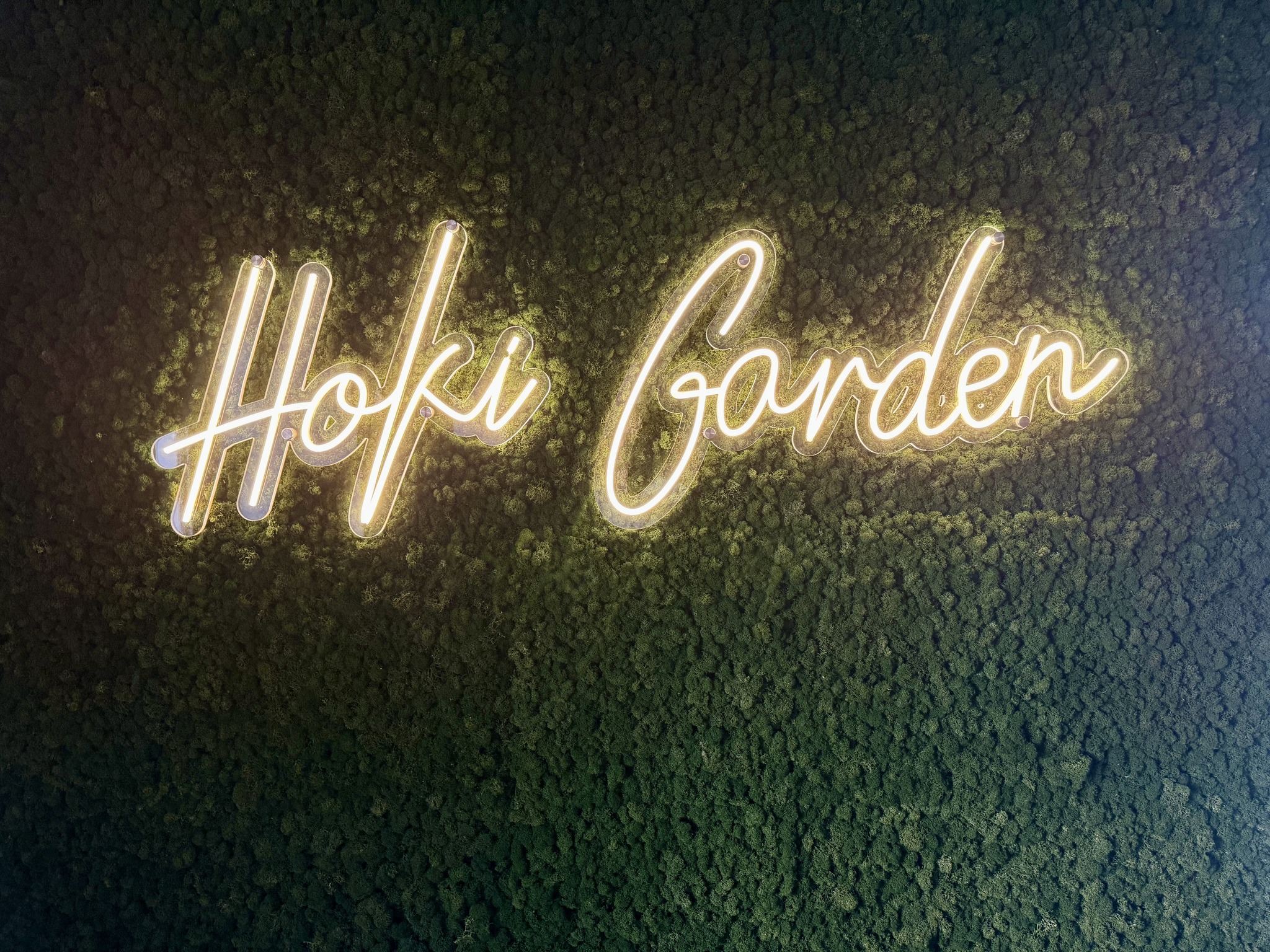 Hoki Garden neonový nápis na živé zelené stěně